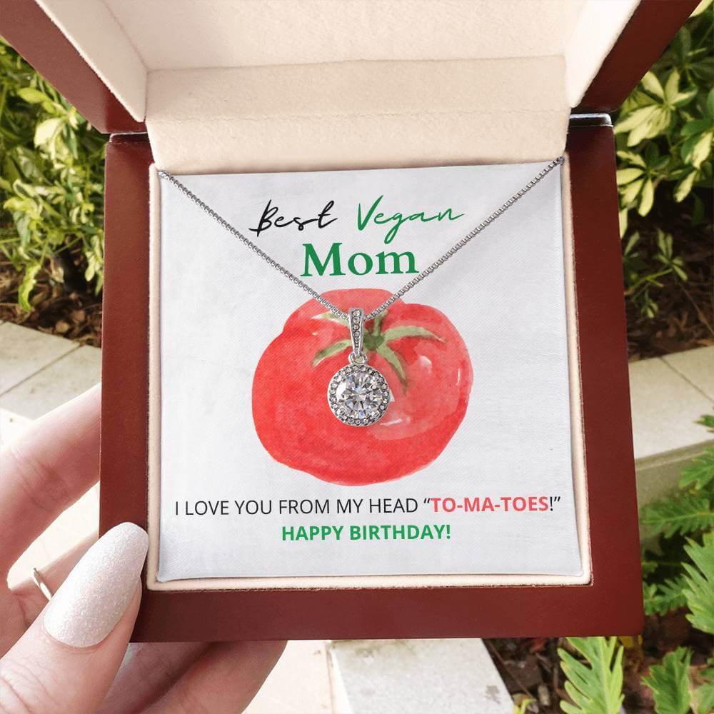 Outdoor shot of Eternal Hope necklace in a wooden box, featuring a tomato-themed birthday card for the best vegan mom.