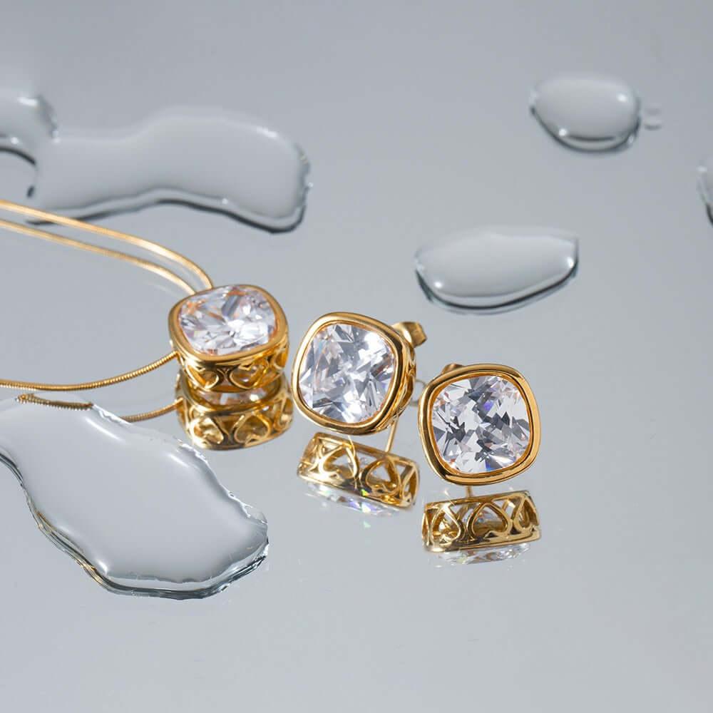 Gold jewelry set with crystal stones on a reflective surface