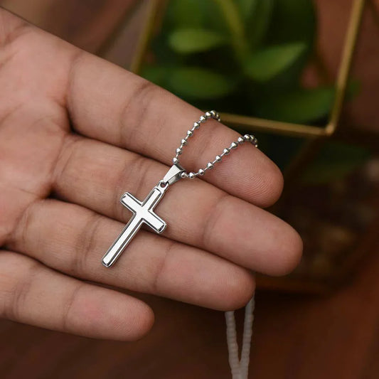 Close-up of stainless steel Faith Cross Necklace held in hand, featuring ball chain. Inspirational Christian jewelry gift for men or women.